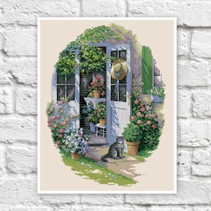 May include: A cross-stitch pattern depicting a white door with a black cat sitting on the porch. The door is surrounded by green plants and flowers, including roses and ivy. A straw hat hangs on the door.