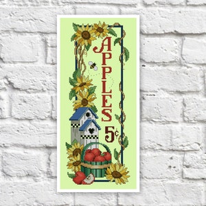 May include: A vintage-style sign with a green background, featuring a basket of red apples, two birdhouses, sunflowers, and the text "APPLES 5¢".