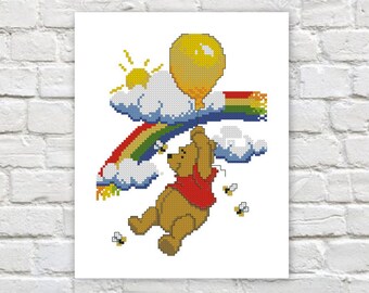 Puede incluir: Un patrón de punto de cruz con Winnie de Pooh sosteniendo un globo amarillo, volando sobre un arcoíris con nubes y abejas.
