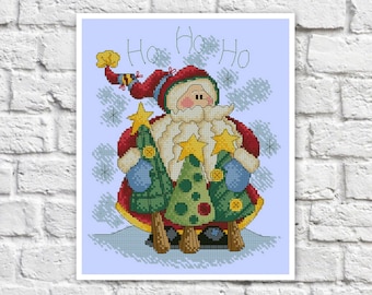 Op de afbeelding: Kruissteekafbeelding van de Kerstman met twee kerstbomen. De Kerstman draagt een rood pak en hoed, blauwe wanten en een witte baard. De woorden "Ho Ho Ho" staan boven het hoofd van de Kerstman. Een feestelijke kerstversiering.