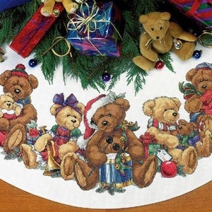 Könnte beinhalten: Ein weißer Christbaumrock mit einem Rand aus Teddybären, die Geschenke halten. Die Bären tragen rote, blaue und grüne Kleidung. Der Rock ist mit grünen Kiefernästen und roten und blauen Ornamenten verziert.