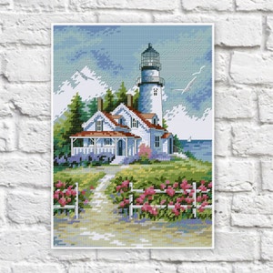 Könnte beinhalten: Ein weißer Leuchtturm mit rotem Dach steht auf einem grasbewachsenen Hügel mit Blick auf ein blaues Meer. Im Vordergrund befindet sich ein weißes Haus mit einer Veranda und einem roten Dach. Im Vordergrund befinden sich rosa Blumen und ein weißer Lattenzaun.