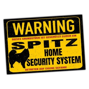 Op de afbeelding: Een geel en zwart waarschuwingsbord met de tekst "WARNING" in grote rode letters. Het bord luidt "DIESES GRUNDSTÜCK IST GESCHÜTZT DURCH EIN SPITZ HOME SECURITY SYSTEM BETRETEN AUF EIGENE GEFAHR!" en toont een zwart silhouet van een Spitz-hond.