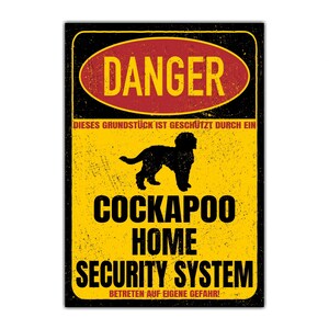Könnte beinhalten: Ein gelbes und schwarzes Warnschild mit dem Text "DANGER" in einem roten Kreis. Das Schild lautet "DIESES GRUNDSTÜCK IST GESCHÜTZT DURCH EIN COCKAPOO HOME SECURITY SYSTEM BETRETEN AUF EIGENE GEFAHR!" und zeigt eine schwarze Silhouette eines Cockapoo-Hundes.