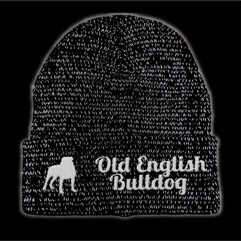 Op de afbeelding: Zwarte gebreide beanie met witte geborduurde tekst en een silhouet van een Old English Bulldog. De tekst luidt "Old English Bulldog". De beanie heeft een donker patroon.