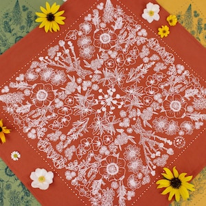 Peut inclure: Un bandana rouge avec un motif floral blanc. Le bandana est entour&eacute; de bandanas plus petits en vert et jaune avec des motifs floraux.