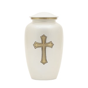 Op de afbeelding: Witte metalen crematie urn met een gouden kruisontwerp.