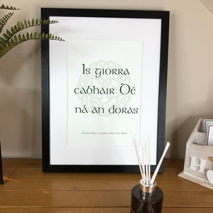 May include: A framed print with a Celtic knot design and the Irish phrase "Is giorra cabhair Dé ná an doras" which translates to "God's help is nearer than the door".