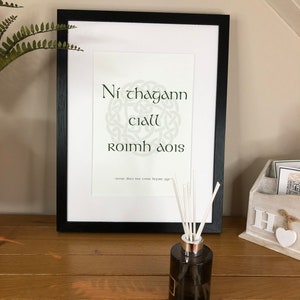 May include: A framed print with a Celtic knot design and the Irish Gaelic phrase "Ni chagann ciall roimh aois" which translates to "Sense does not come before age".