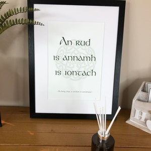 May include: A framed print with a Celtic knot design and the Irish phrase "An rud is annamh is iontach" which translates to "A thing that is seldom is wonderful".