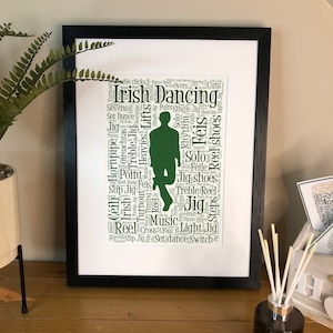 May include: A framed green and white word cloud art print with the silhouette of a person dancing. The word cloud features terms related to Irish dancing, such as "Irish Dancing", "Jig", "Reel", "Set Dance", "Treble Jig", "Hornpipe", "Heavies", "Lifts", "Point", "Single Jig", "Solo", "Rhythm", "Féis", "Jig shoes", "Treble Reel", "Red shoes", "Cross", "Light", "Switch", "Céilí", "Turnout", "Timing", "Music", "Oireachtas", "Cuts", "Sevens", "Set Dance", "Thing", "Hes", "Solo", "Féile", "Solo", "Jig shoes", "Treble Reel", "Red shos", "Jig", "Music Pure Line", "Reel Cross Cross Light Jig", "Turtout", "Slip JigSet dance Switch".