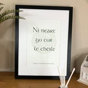 May include: A framed print with a green Celtic knot design and the Irish Gaelic phrase "Ni neart go cur le chéile" which translates to "There is no strength without unity".