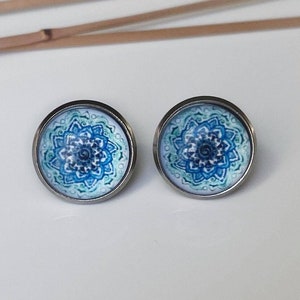 May include: A pair of silver stud earrings with a blue and green mandala design.