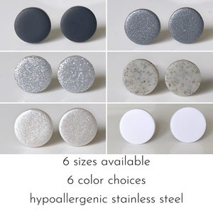 May include: Six pairs of hypoallergenic stainless steel stud earrings in six different colours and finishes: black, silver glitter, white glitter, speckled grey, white, and silver.