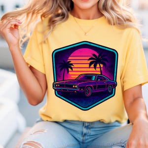 Könnte beinhalten: Gelbes T-Shirt mit einem Retro-Design eines lila Autos, Palmen und einem Sonnenuntergang. Die Grafik ist in einem teal- und schwarzen Sechseck eingeschlossen. Das Shirt ist aus einem weichen Material und für Freizeitkleidung geeignet.