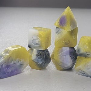 May include: A set of seven dice with a yellow, white, and purple marbled pattern. The dice are numbered 1 through 6 and have a unique design on each side.