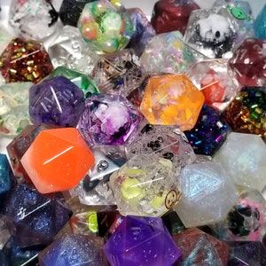 May include: A collection of colorful, multi-sided dice with various designs and patterns. The dice are made of clear plastic and have a variety of colors, including purple, orange, green, blue, and red.