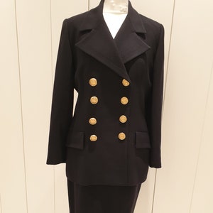 May include: A black double-breasted blazer with gold buttons and a matching skirt. The blazer has a notched collar and long sleeves.