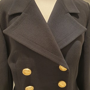 May include: A black double-breasted blazer with gold buttons. The blazer has a wide collar and a fitted silhouette.