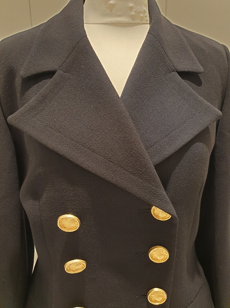 May include: A black double-breasted blazer with gold buttons. The blazer has a wide collar and a fitted silhouette.