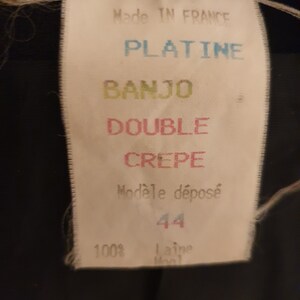 May include: White tag with black text that reads "Made in France", "Platine", "Banjo", "Double Crepe", "Mod&egrave;le d&eacute;pos&eacute;", "44", and "100% laine wool".