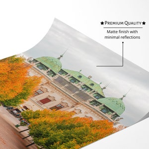 May include: A photograph of a building with a green roof and yellow walls. The building is surrounded by trees with yellow leaves. The ground is covered in fallen leaves.