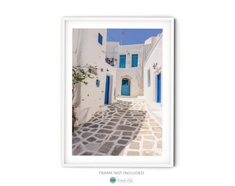 May include: A narrow, whitewashed alleyway with blue doors and windows in a Greek village. The cobblestone path leads to a bright blue door at the end of the alley.