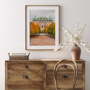 May include: A framed photograph of a white building with green domes and a pathway lined with trees in autumn. The trees have orange leaves and the ground is covered in fallen leaves.
