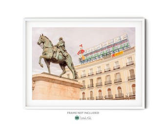 May include: A bronze statue of a man on horseback in front of a building with a large sign that reads "EL CORTE INGLES".