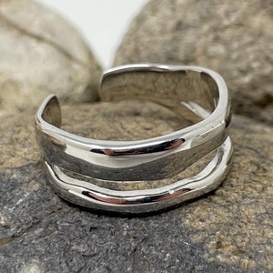 May include: A silver ring with a double band design. The ring is made of smooth, polished metal and has a simple, modern style.