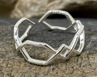 May include: A silver ring with a geometric design. The ring is made of a series of connected hexagons.