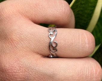 May include: A silver ring with a delicate, intricate design featuring a series of connected swirls.