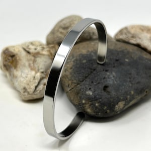 May include: A silver metal bangle bracelet with a smooth, polished finish.
