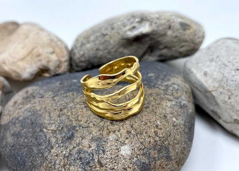 May include: Gold ring with a textured, wavy design. The ring is made of multiple bands that are intertwined.