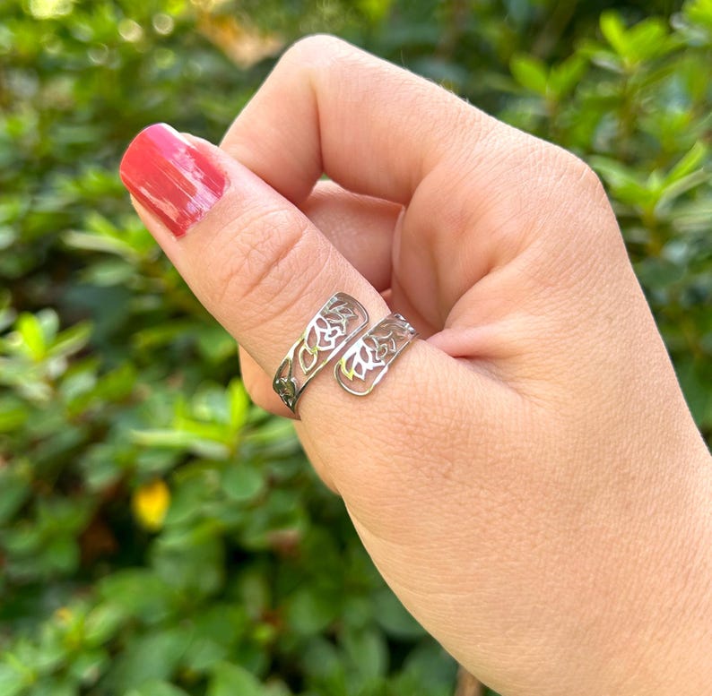 May include: A silver thumb ring with a delicate floral design. The ring is open and adjustable to fit most thumb sizes.