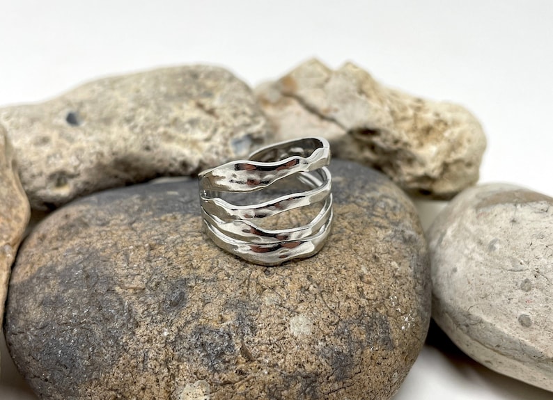 May include: Silver ring with a hammered, wavy design. The ring is made of multiple bands that are stacked on top of each other.