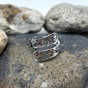 May include: A silver ring with a delicate, intricate design of swirling leaves. The ring is open and adjustable to fit different finger sizes.