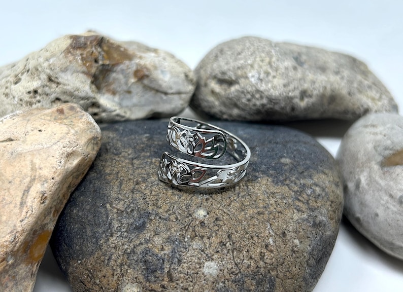 May include: A silver toe ring with a Celtic knot design. The ring is on a gray rock.