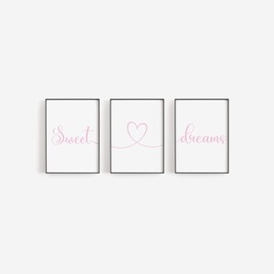 May include: Three framed prints with black frames and white backgrounds. The left print has the word "Sweet" in pink cursive. The middle print has a pink heart drawn with a line. The right print has the word "dreams" in pink cursive.