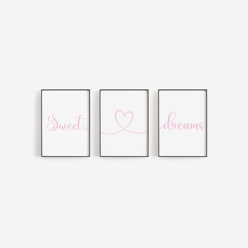 May include: Three framed prints with black frames and white backgrounds. The left print has the word "Sweet" in pink cursive. The middle print has a pink heart drawn with a line. The right print has the word "dreams" in pink cursive.