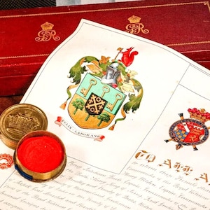 May include: An antique document with a colorful coat of arms, a red wax seal, and a gold seal. The document is on a white background, with a red box in the background. The seals and box have ornate designs.