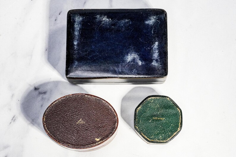 May include: A rectangular dark blue box with a worn finish, a brown oval box with a textured surface, and a small green octagonal box. The brown box features the text "MADE IN ITALY" and the green box also features the text "MADE IN ITALY".