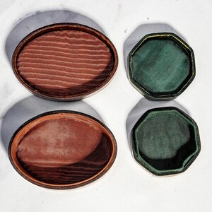 May include: Two oval-shaped containers with dark brown exteriors and textured reddish-brown fabric linings, alongside two octagonal-shaped containers with dark green exteriors and smooth dark green fabric linings, all viewed from directly above.