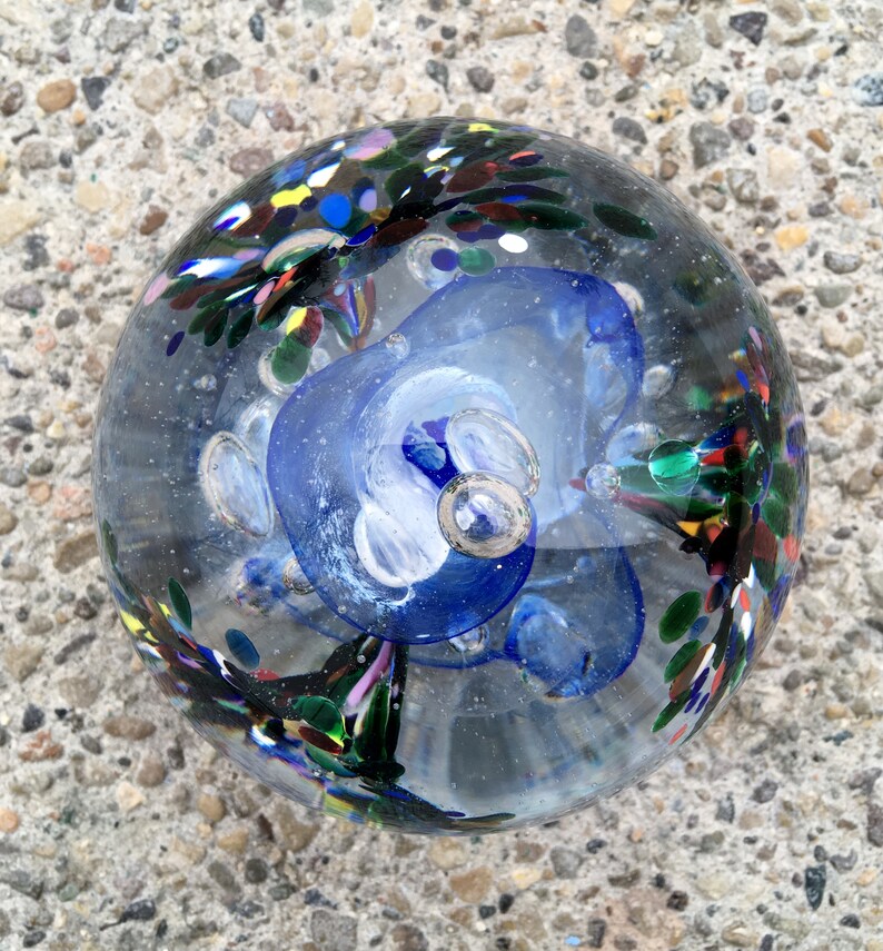 Blue and Red Mix BlueWhite center with Green Blown Glass Large Tri-Flower Paperweight on a Dark Wooden Light Box