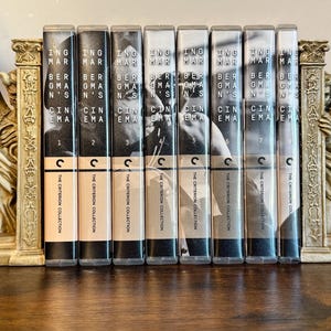 May include: A set of eight black VHS tapes with white text. The tapes are labeled "Bergman's Cinema" and numbered 1 through 8. The tapes are arranged in a row on a wooden surface. The Criterion Collection logo is visible on each tape.