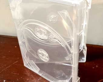 May include: A clear plastic case with two slots for storing DVDs or Blu-ray discs. The case is open and the slots are visible.