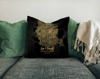 Puede incluir: Una almohada negra con un mapa dorado de una ciudad y un corazón rosa marcando una ubicación. El texto "Lisa & Vincent Where It All Began October 8, 2021" está impreso en la almohada.