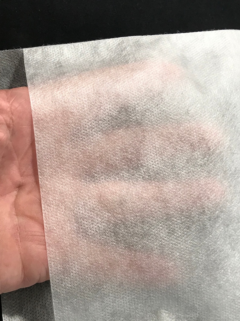 Puede incluir: Primer plano de una tela no tejida blanca con una superficie texturizada. La tela es suave y ligera.