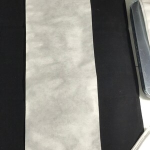 Puede incluir: Una hoja rectangular blanca de tejido no tejido, a menudo utilizada para presionar o planchar telas delicadas.