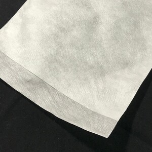 Puede incluir: Primer plano de una tela no tejida blanca con una costura a lo largo del borde.